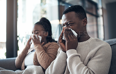Buy stock photo Cropped shot of a young couple sitting in their living room together and feeling sick while blowing their nose