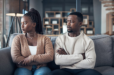 Buy stock photo Cropped shot of a young couple sitting on the sofa and giving each other the silent treatment after an argument