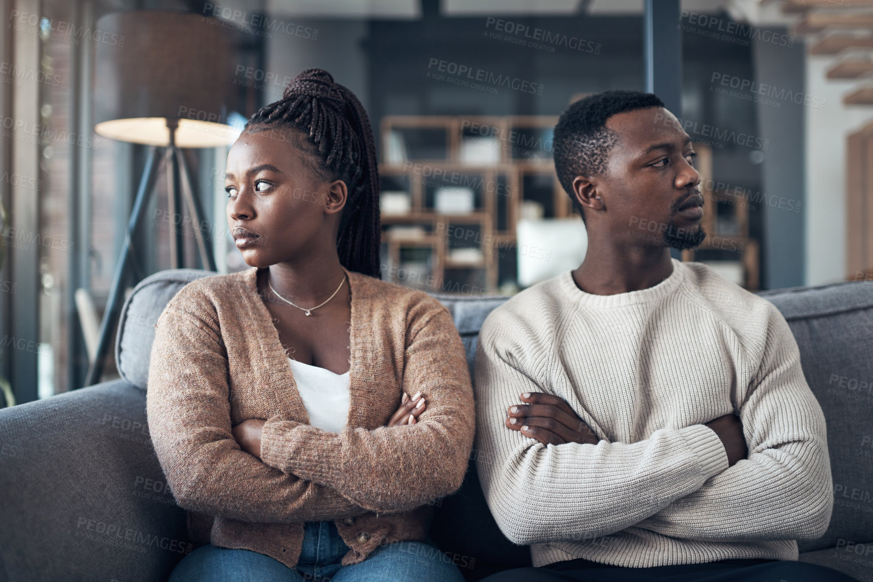 Buy stock photo Cropped shot of a young couple sitting on the sofa and giving each other the silent treatment after an argument