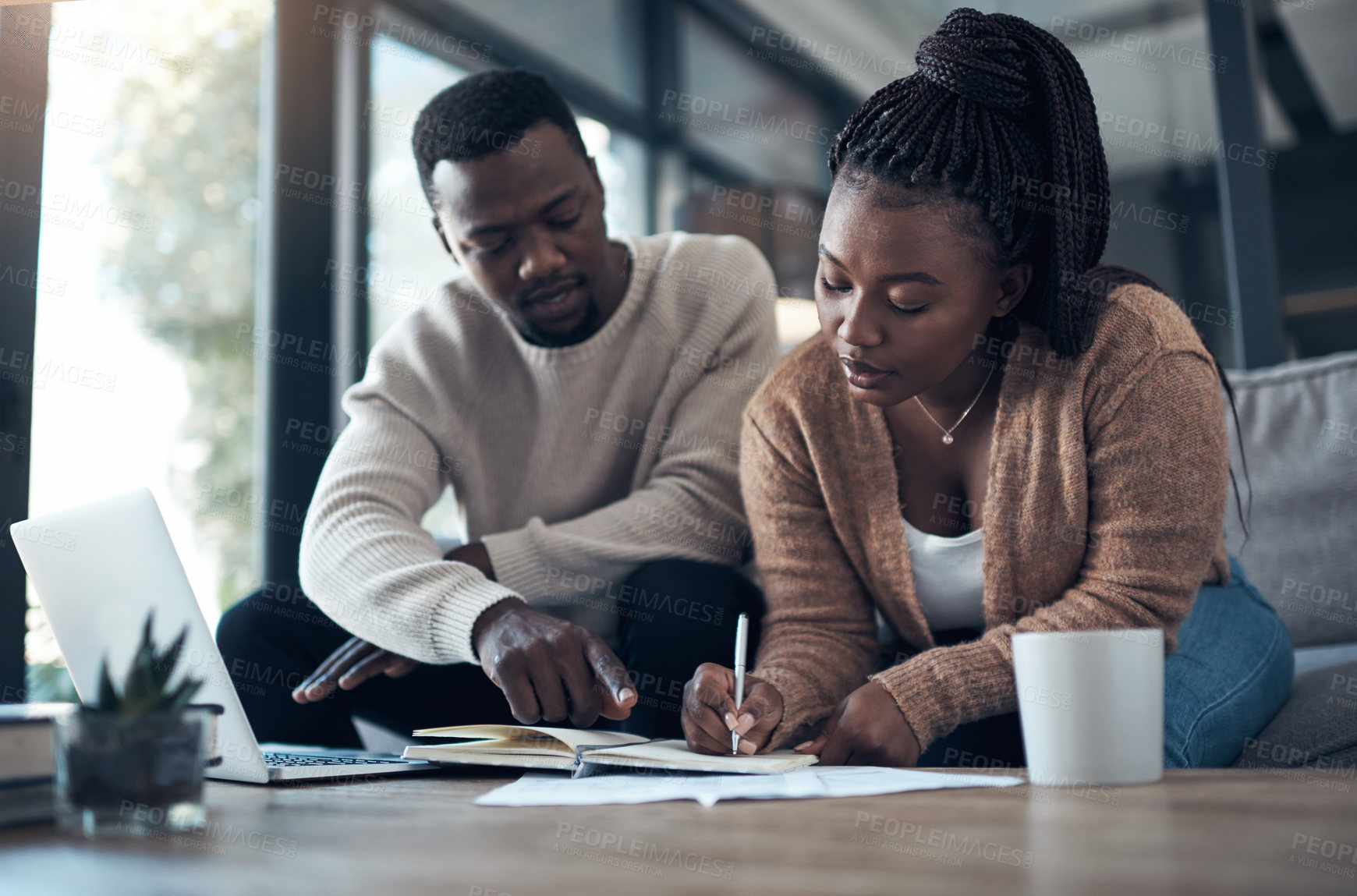 Buy stock photo Cropped shot of a young couple sitting on the sofa together and using a laptop while going through their finances