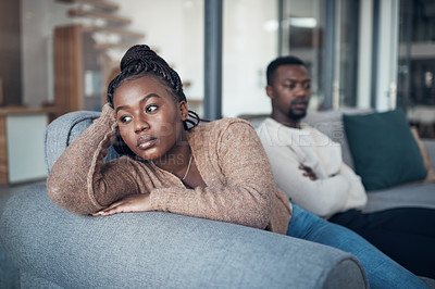 Buy stock photo Cropped shot of a young couple sitting on the sofa and giving each other the silent treatment after an argument