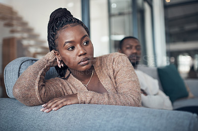 Buy stock photo Cropped shot of a young couple sitting on the sofa and giving each other the silent treatment after an argument