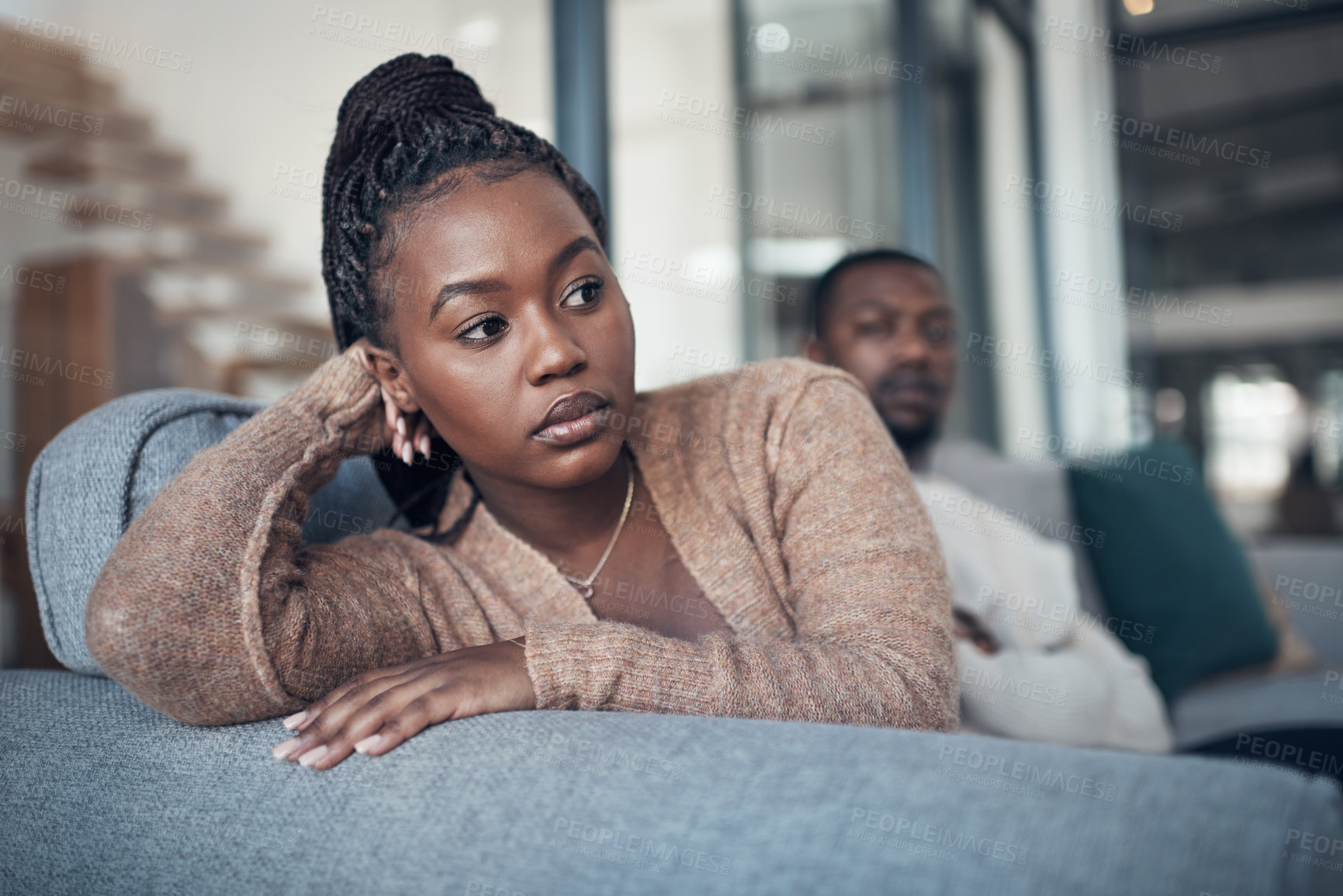 Buy stock photo Cropped shot of a young couple sitting on the sofa and giving each other the silent treatment after an argument