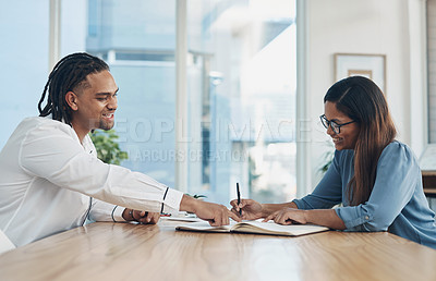 Buy stock photo Shot of two businesspeople going through paperwork together in an office