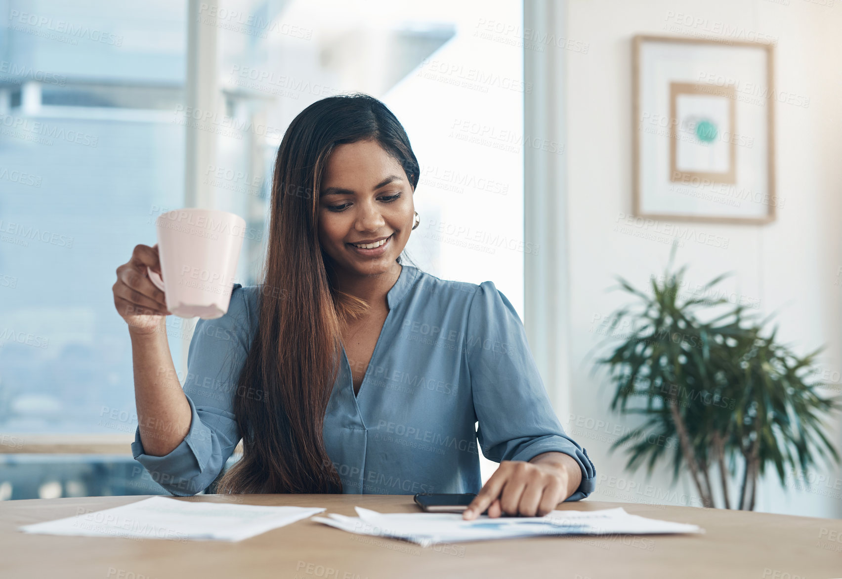 Buy stock photo Shot of a young businesswoman drinking coffee while working in an office