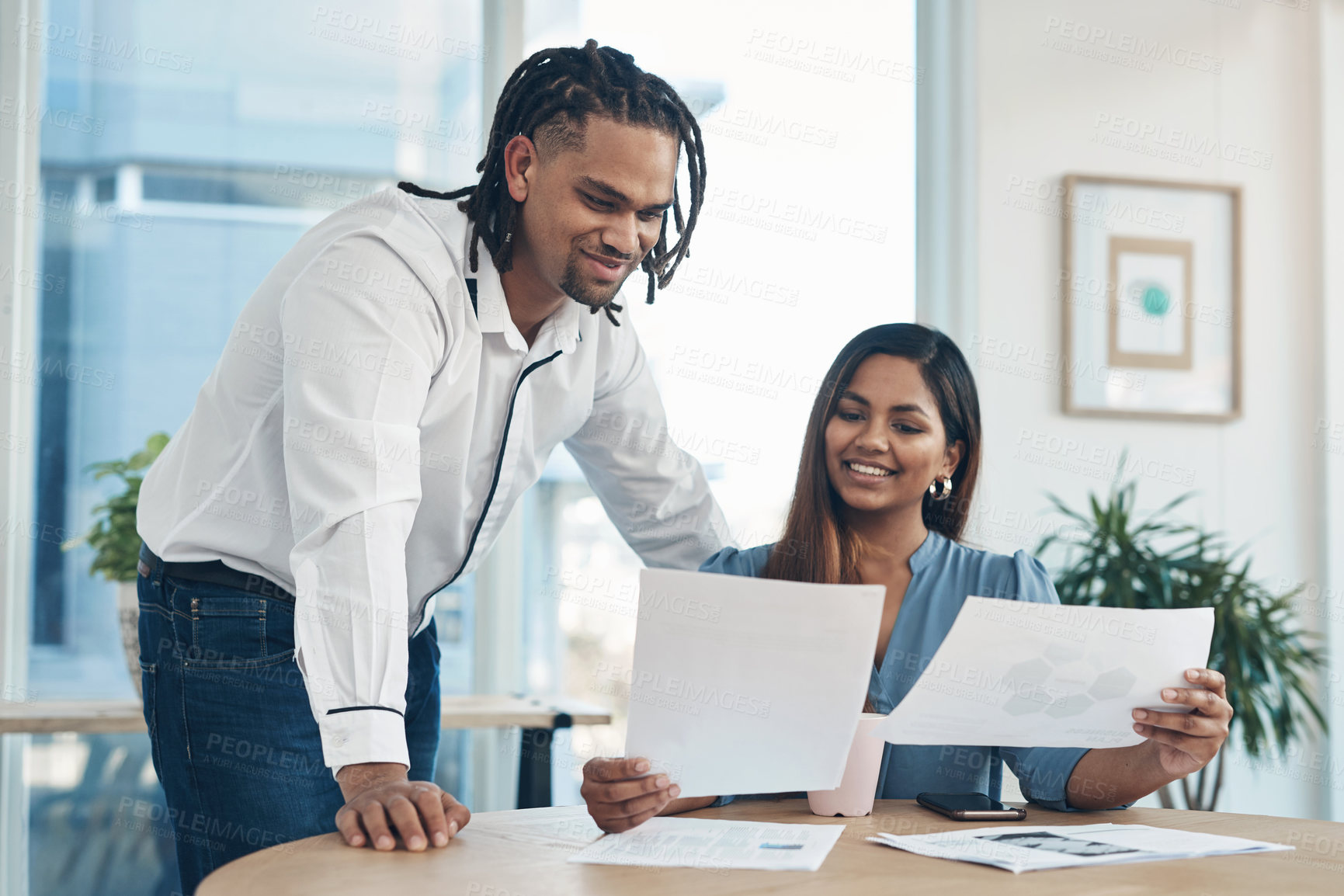 Buy stock photo Shot of two businesspeople going through paperwork together in an office