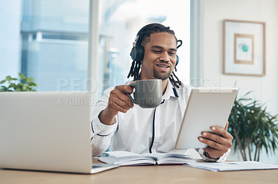 Buy stock photo Shot of a young businessman wearing headphones while using a digital tablet in an office