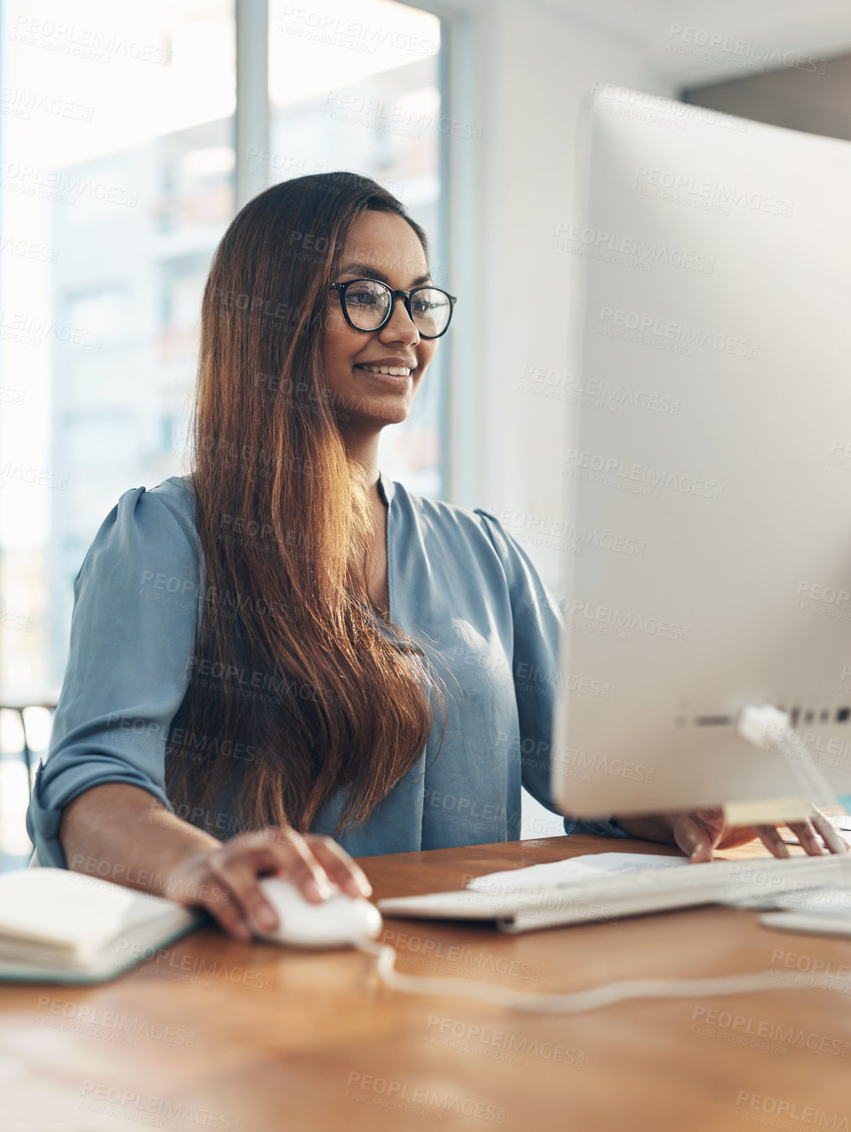 Buy stock photo Shot of a young businesswoman working on a computer in an office