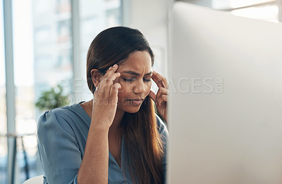 Buy stock photo Shot of a young businesswoman experiencing a headache while working on a computer in an office