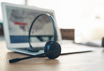 Buy stock photo Still life shot of a headset and laptop on table in an office