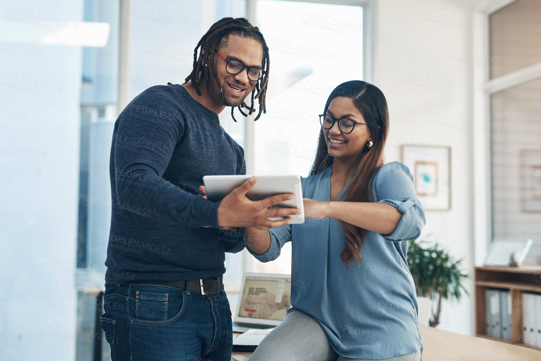 Buy stock photo Shot of two businesspeople using a digital tablet together in an office