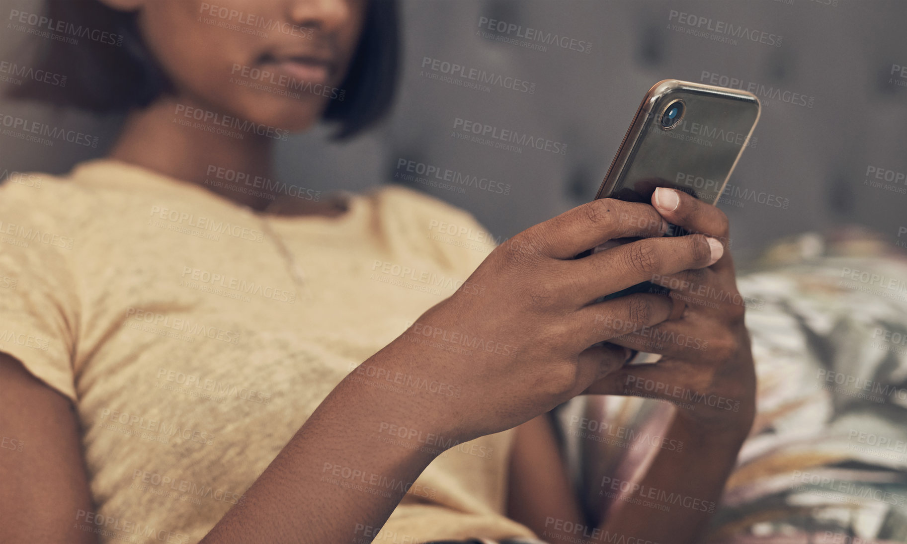 Buy stock photo Shot of a woman using a smartphone while relaxing on her bed at home