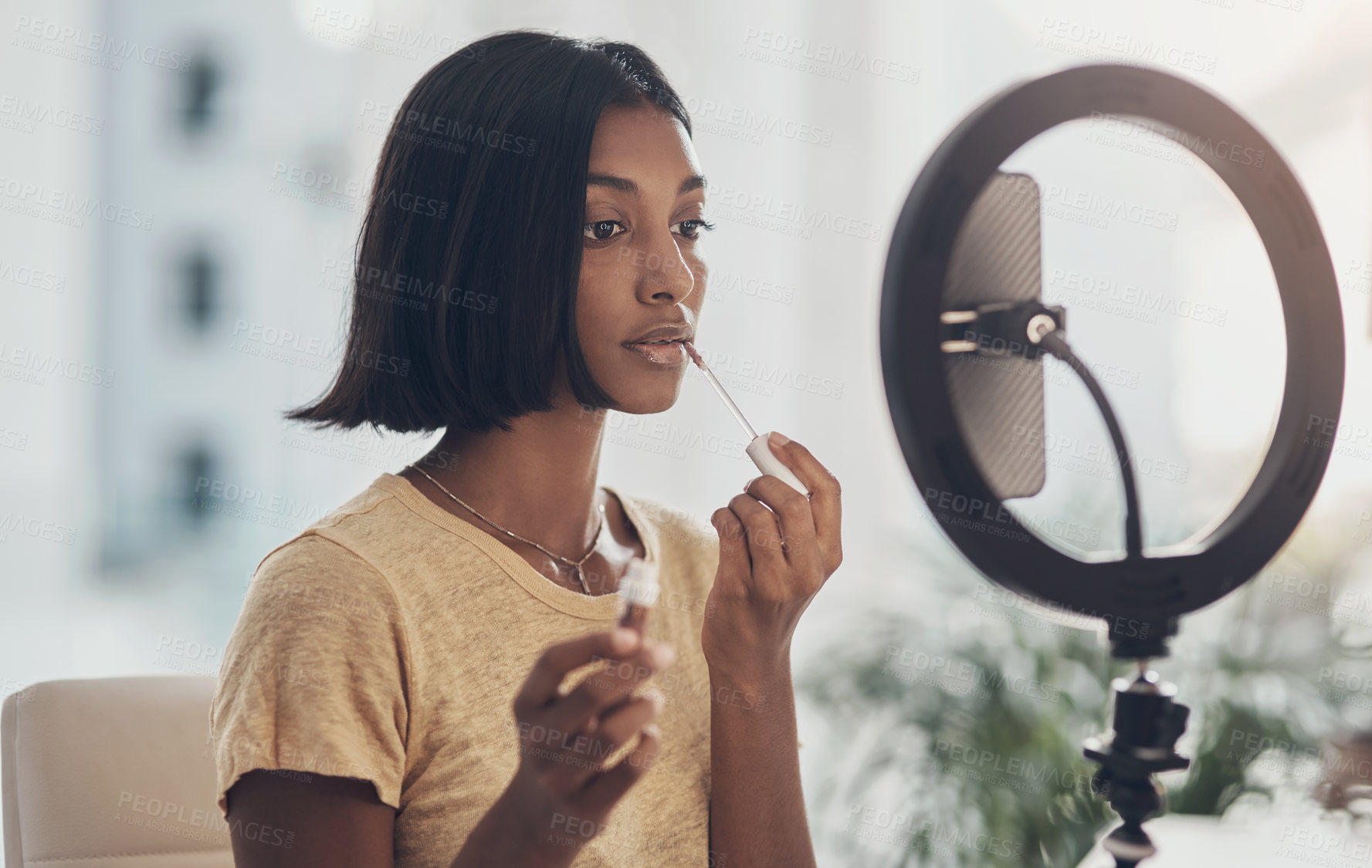 Buy stock photo Shot of a young woman applying makeup while filming a beauty tutorial at home