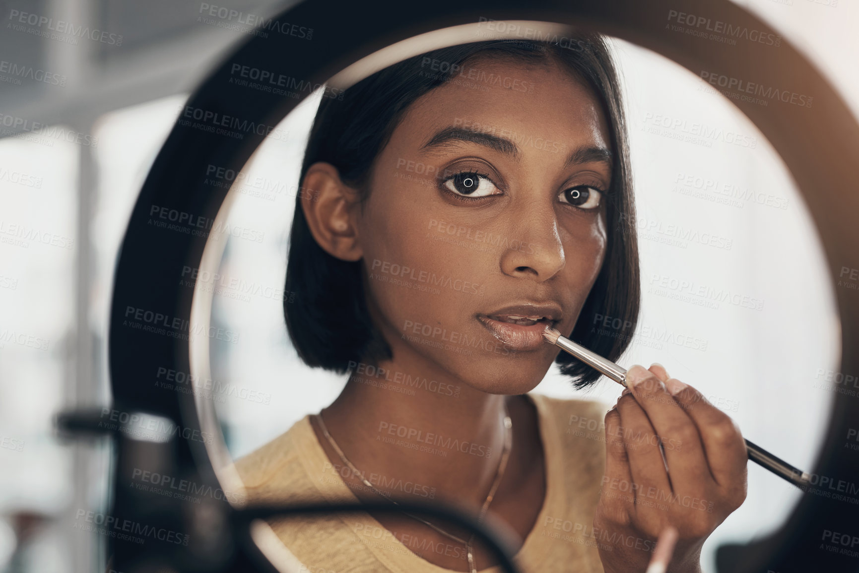 Buy stock photo Shot of a young woman applying makeup while filming a beauty tutorial at home