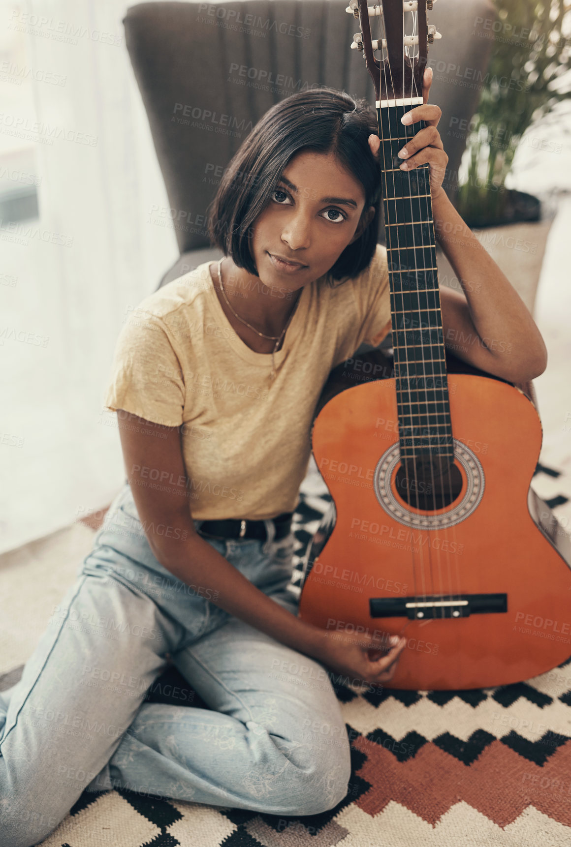 Buy stock photo Portrait of a young woman playing the guitar at home