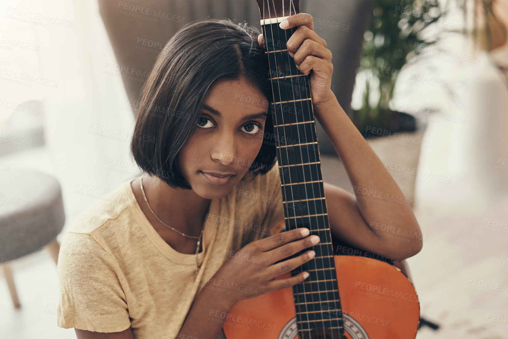 Buy stock photo Portrait of a young woman playing the guitar at home