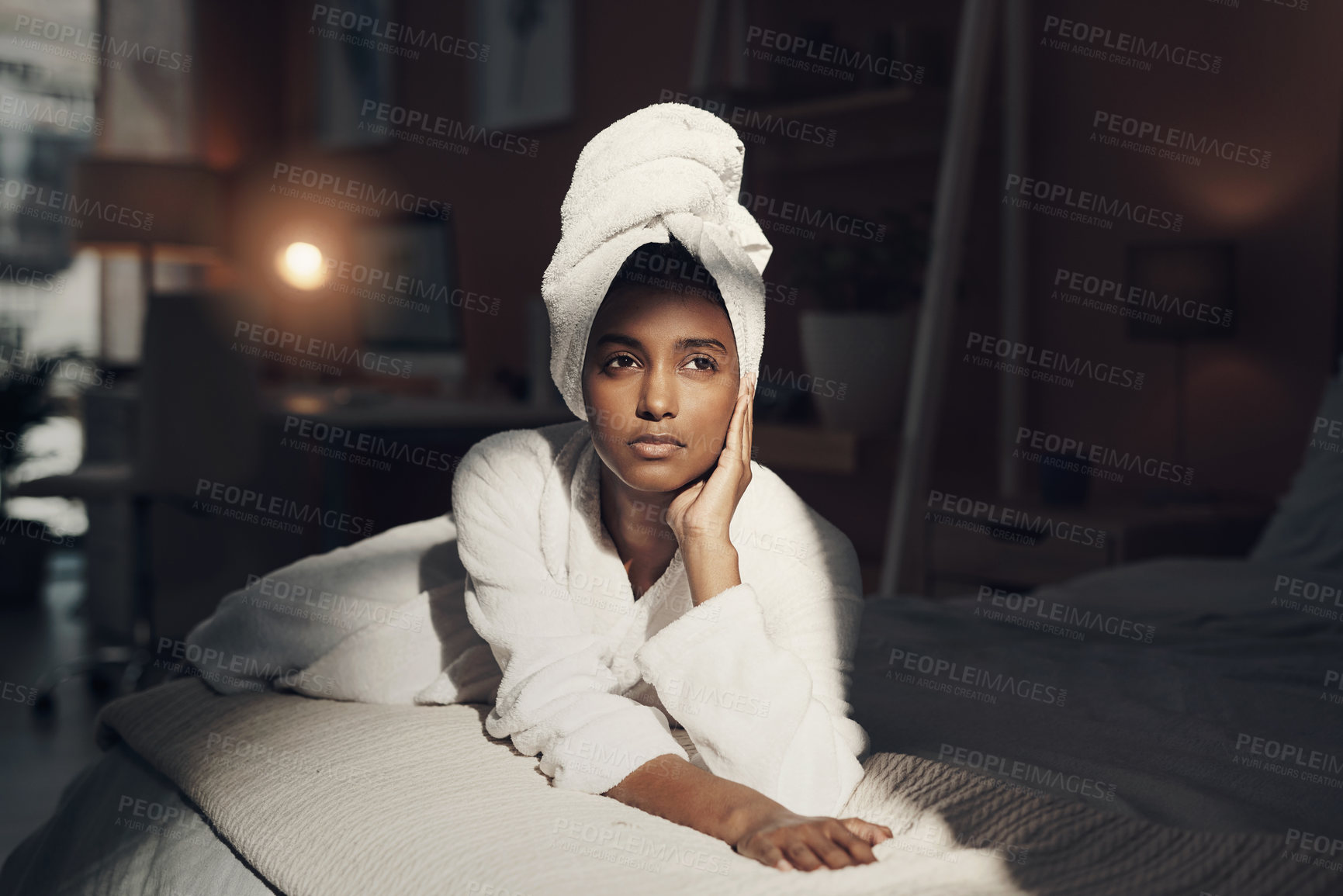Buy stock photo Shot of a young woman relaxing on her bed while going through her beauty routine at home