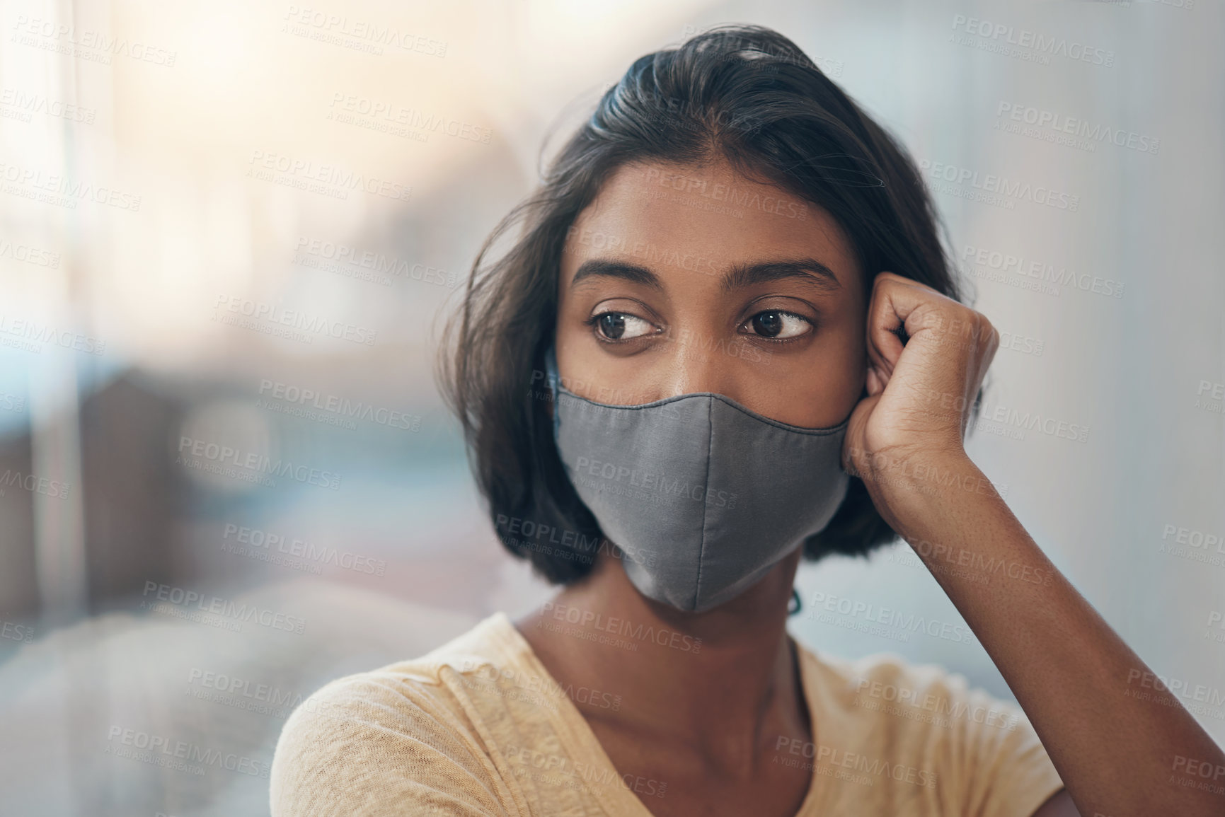 Buy stock photo Shot of a young woman wearing a face mask and looking thoughtful