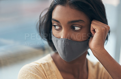 Buy stock photo Shot of a young woman wearing a face mask and looking thoughtful