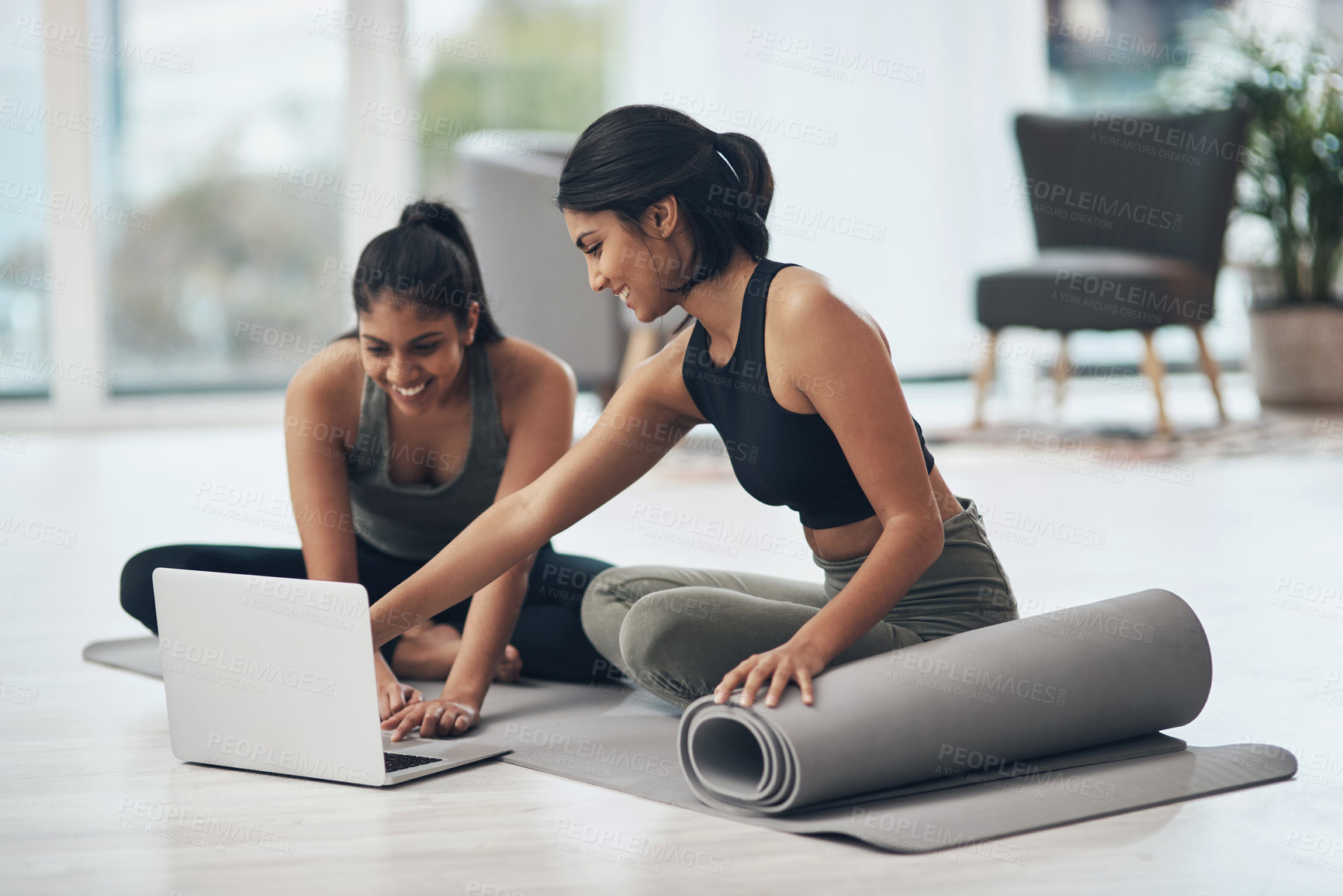 Buy stock photo Shot of two young women using a laptop while working out at home