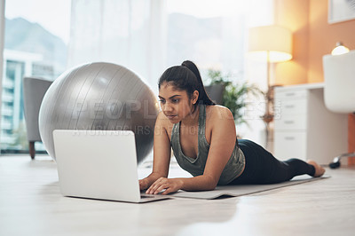 Buy stock photo Shot of a woman using her laptop while exercising at home