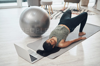 Buy stock photo Shot of a woman working out in her living room with her laptop in front of her