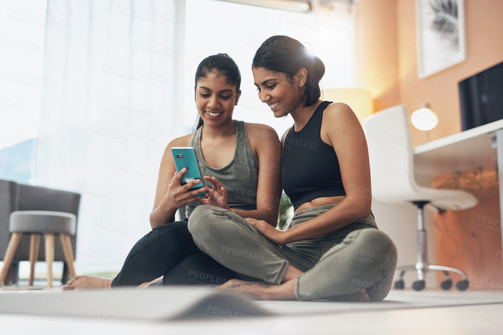 Buy stock photo Exercise, phone and women together on home floor with internet for social media app. Indian sisters or female friends in lounge with smartphone for online class, chat or fitness workout with partner