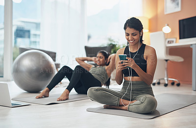 Buy stock photo Shot of a woman listening to music through her cellphone while exercising at home