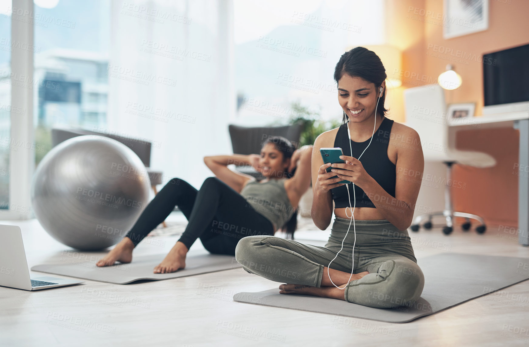 Buy stock photo Shot of a woman listening to music through her cellphone while exercising at home