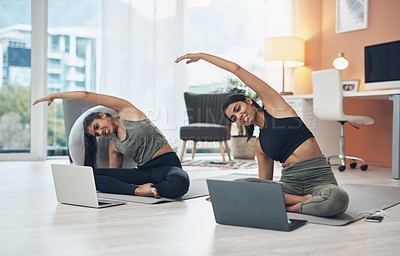 Buy stock photo Shot of two young women using their laptops while working out at home