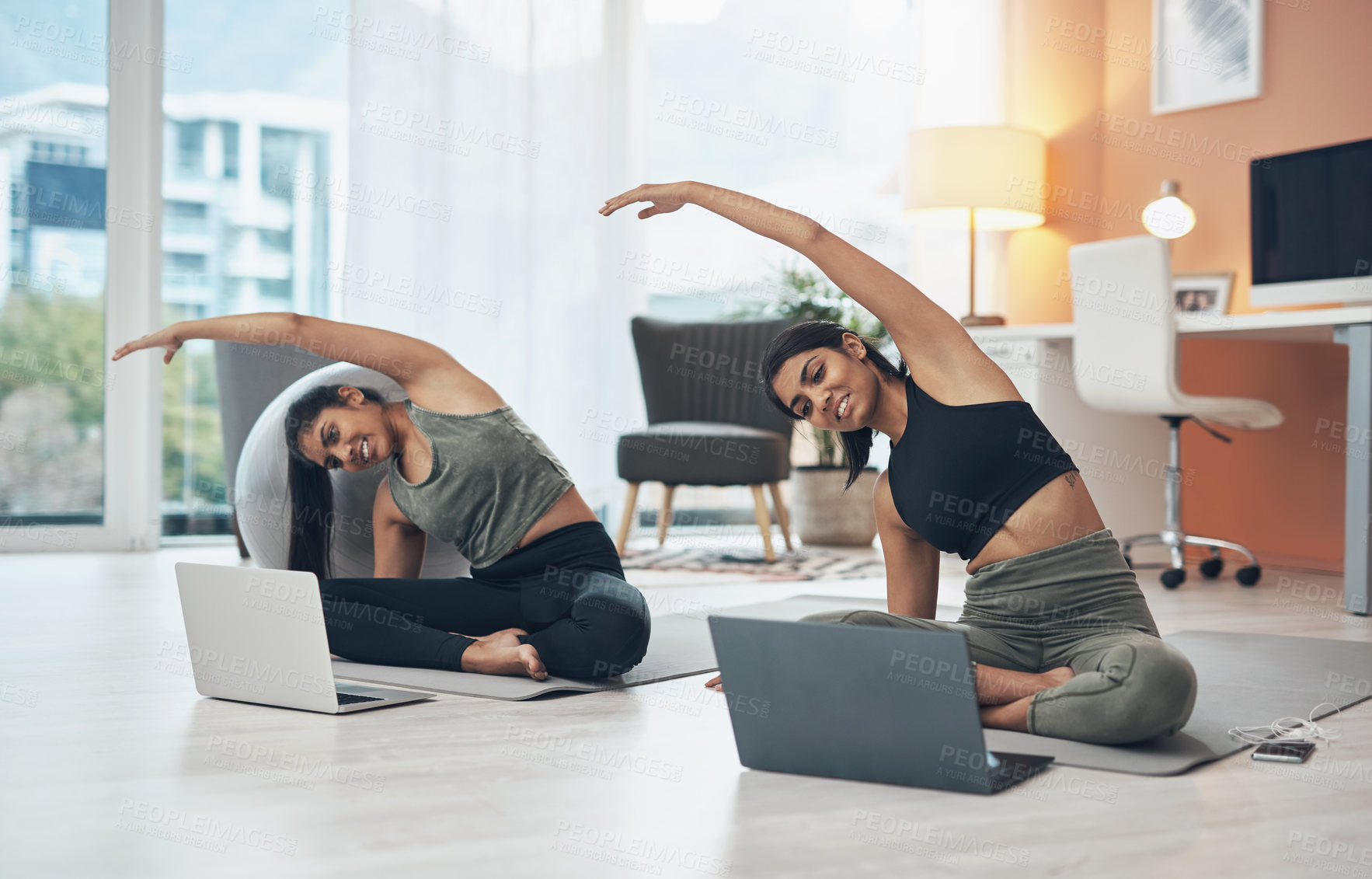 Buy stock photo Shot of two young women using their laptops while working out at home