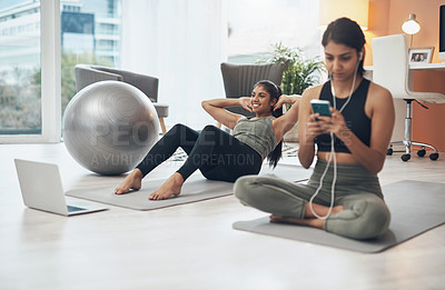 Buy stock photo Shot of a woman listening to music through her cellphone while exercising at home