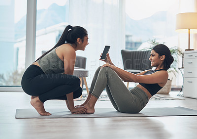 Buy stock photo Shot of two beautiful young women exercising together at home