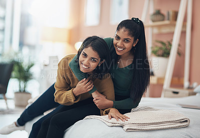 Buy stock photo Shot of two happy young women sitting together at home