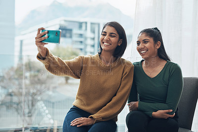 Buy stock photo Shot of two young women taking a selfie together while sitting at home