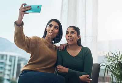 Buy stock photo Shot of two young women taking a selfie together while sitting at home