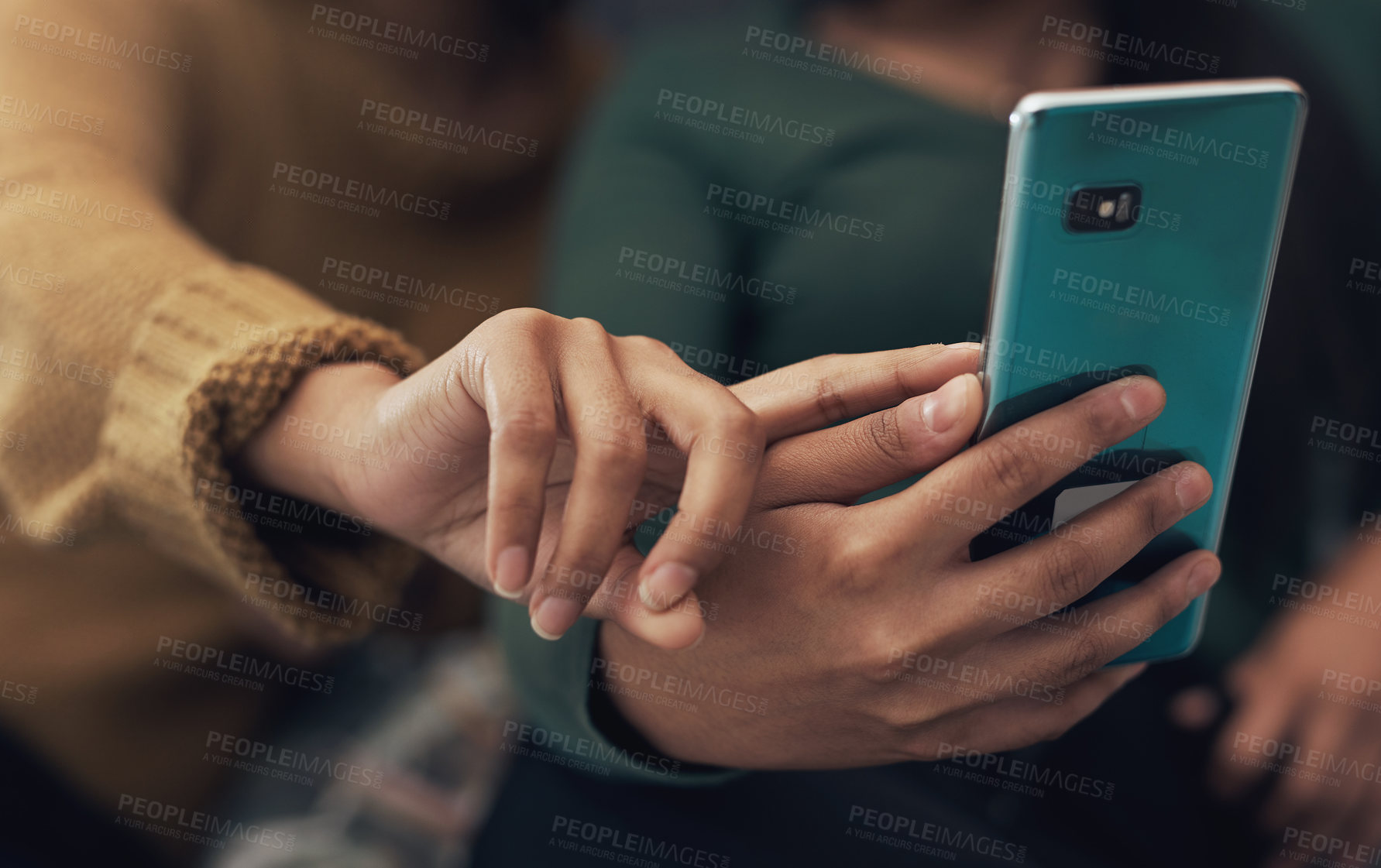 Buy stock photo Cropped shot of two unrecognisable women looking at something on a cellphone together