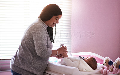 Buy stock photo Shot of a young woman changing her baby girl’s diaper at home