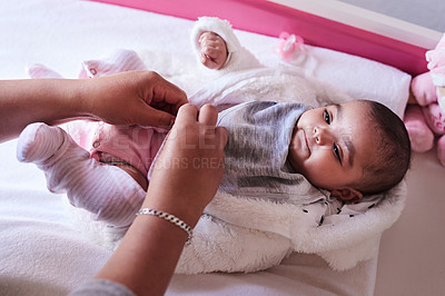 Buy stock photo Shot of a woman changing her baby girl’s clothing at home