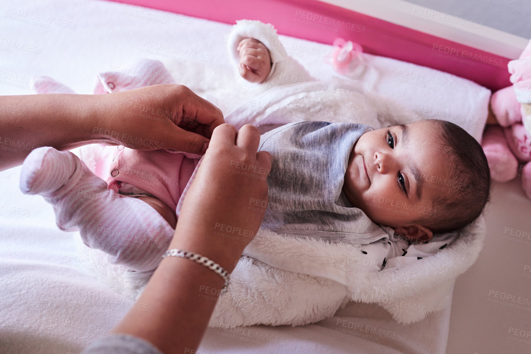 Buy stock photo Shot of a woman changing her baby girl’s clothing at home