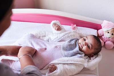 Buy stock photo Shot of a woman changing her baby girl’s clothing at home