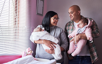 Buy stock photo Shot of a young man and woman carrying their twin baby girls at home