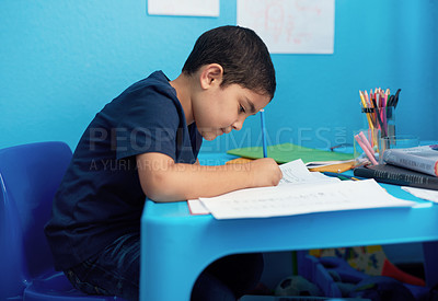 Buy stock photo Shot of an adorable little boy completing a school assignment at his desk