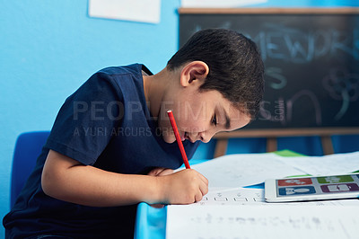 Buy stock photo Shot of an adorable little boy completing a school assignment at his desk