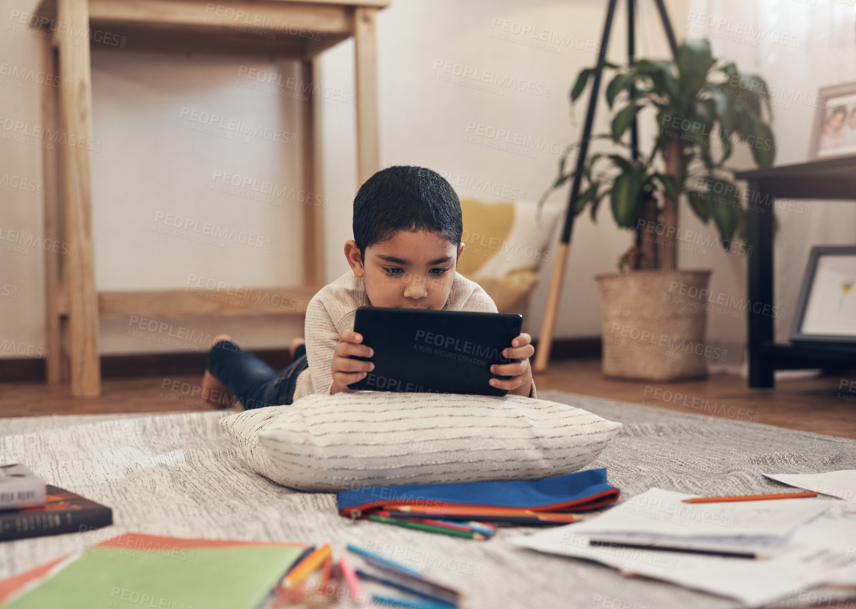 Buy stock photo Shot of an adorable little boy using a digital tablet and headphones while completing a school assignment at home