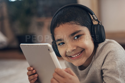 Buy stock photo Shot of an adorable little boy using a digital tablet and headphones at home