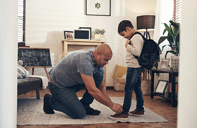 Buy stock photo Shot of an adorable little boy getting his shoelaces tied by his father before leaving to go to school