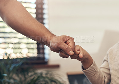 Buy stock photo Shot of an unrecognisable little boy bumping fists with his father at home