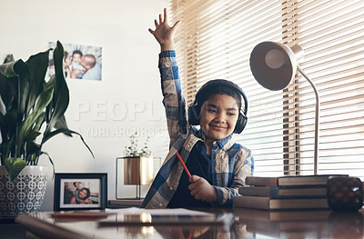 Buy stock photo Shot of an adorable little boy using headphones and raising his hand while completing a school assignment at home