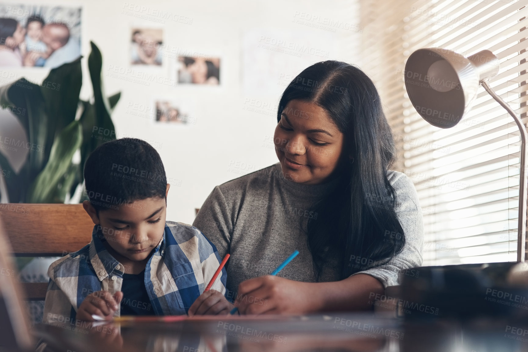 Buy stock photo Shot of an adorable little boy completing a school assignment with his mother at home